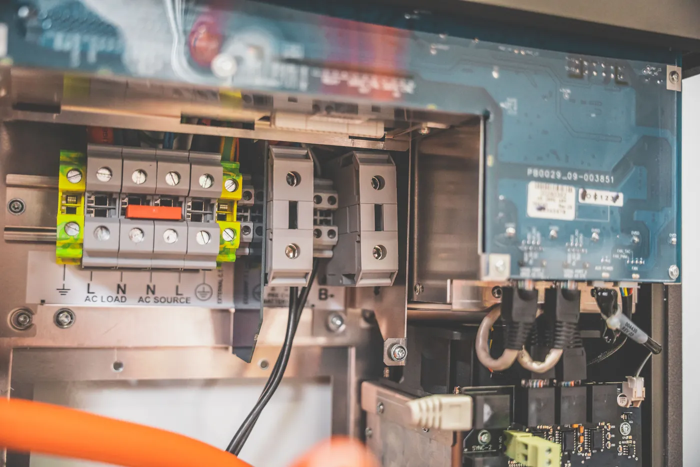 Anschlussklemmen und Steuerplatine im geöffneten Gehäuse eines Wechselrichters mit orangefarbenem Kabel (Oberwesel, Rhein-Hunsrück-Kreis)