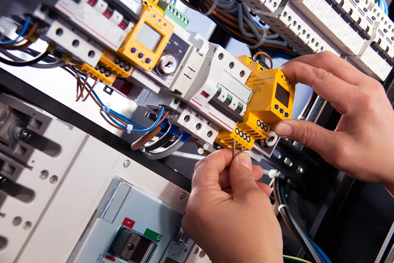 Hände verdrahten ein Schutzgerät auf der Hutschiene eines Verteilerschranks mit Leitungsschutzschaltern (Gersheim, Saarpfalz-Kreis)