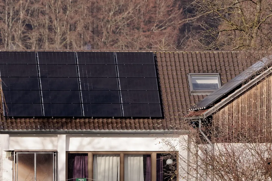 Schwarze Solarmodule auf dem braunen Ziegeldach eines Wohnhauses mit Holzverkleidung (Vörstetten, Landkreis Emmendingen)
