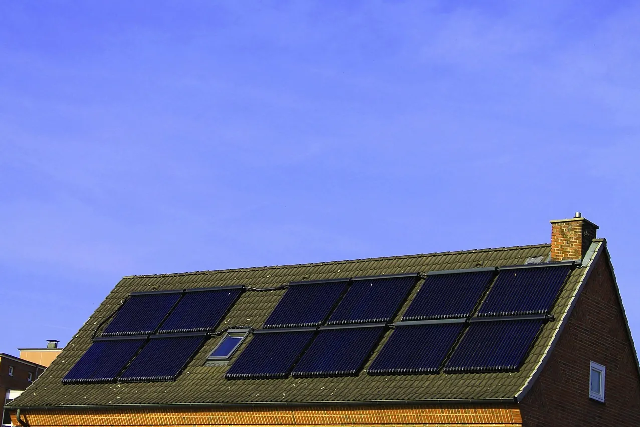 Solarmodule und ein Dachfenster auf dem bemoosten Satteldach eines Backsteinhauses (Loiching, Landkreis Dingolfing-Landau)