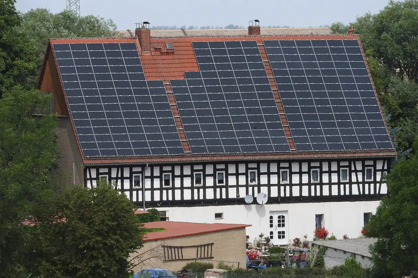 Fachwerkhaus mit Solarmodulen auf fast der ganzen roten Dachfläche, davor ein Garten (Buchholz in der Nordheide, Landkreis Harburg)