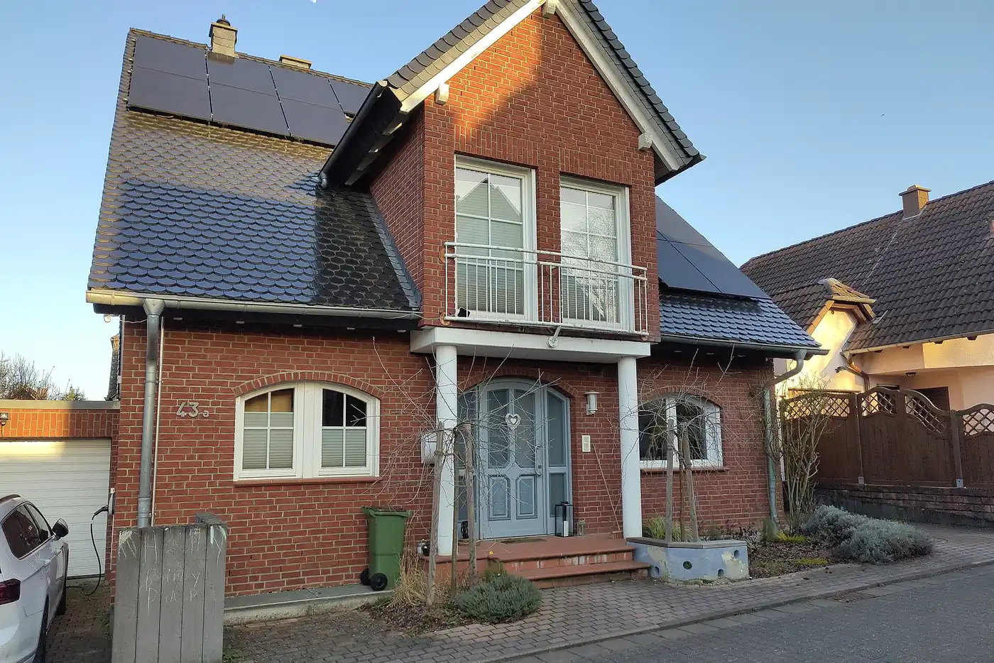Einfamilienhaus aus rotem Klinker mit schwarzen Solarmodulen auf dem dunklen Dach (Langenhahn, Westerwaldkreis)